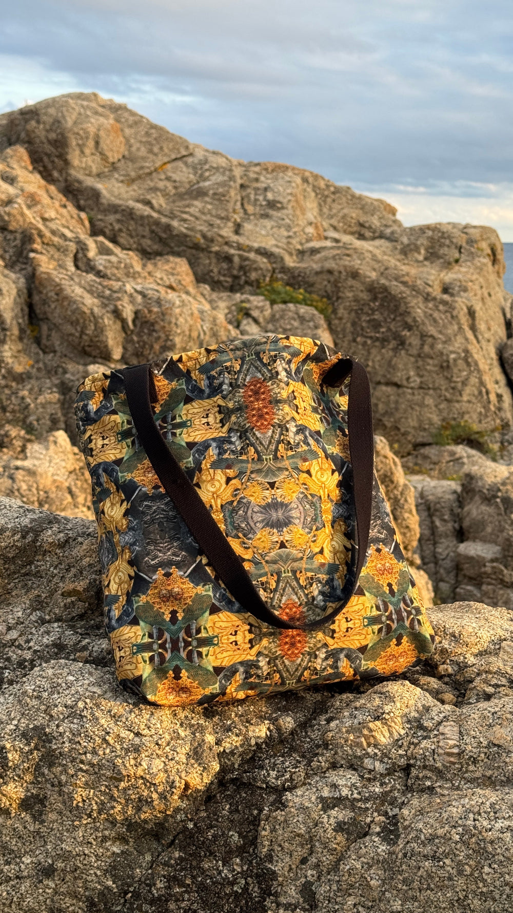Patterned tote bag on a rocky surface with a mountainous background